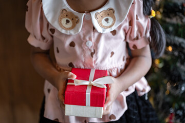 Close-up of Child Holding a Red and White Gift Box with Cream Bow, Cute Christmas Present