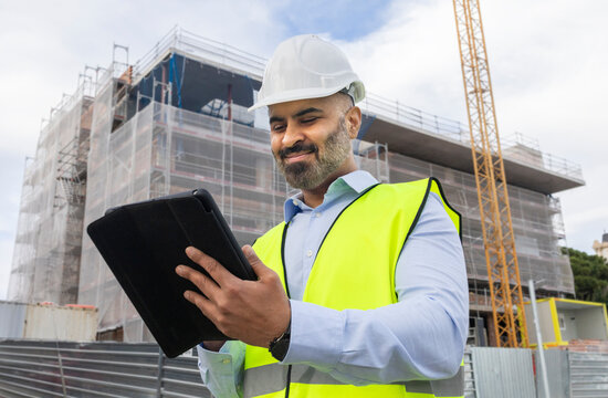 Engineer reviewing plans on construction site with tablet
