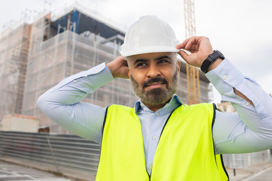 Engineer adjusting hard hat on construction site
