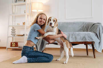 Smiling, having fun. Girl is with her dog on the floor in a cozy living room