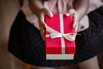Child's Hands Holding a Carefully Wrapped Red and White Present for Christmas or New Year Gift Giving