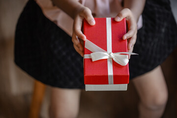 Child Presenting a Special Red and White Christmas Gift Box Towards the Viewer, Close-up Shot