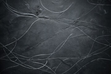 Dark gray slate surface with white scratches and marks, abstract background texture
