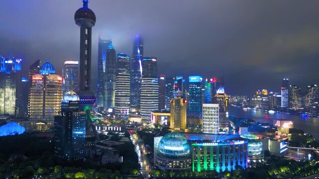 Aerial view of the brightly lit, modern Lujiazui financial district skyline featuring the iconic Oriental Pearl Tower at night in Shanghai, China.