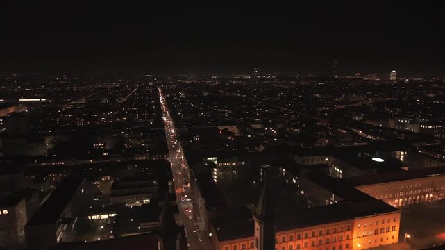 Panoramische Luftaufnahme Muenchen, Deutschland bei Nacht mit Ludwigstrasse, St Ludwig Kirche, Siegestor, Universitaetsviertel, beleuchteten Strassen, Verkehr und stimmungsvollem urbanem Nachtleben