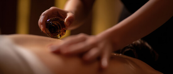 Close-up of therapist massaging client's back with oil