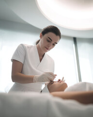 Professional cosmetologist performing facial treatment procedure
