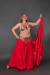 Smiling and happy curvy woman dancer dressing in dancing costume - bra top and red skirt, performing