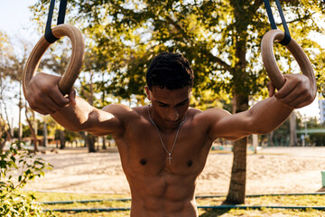 Athlete resting on gymnastic rings during outdoor calisthenics training
