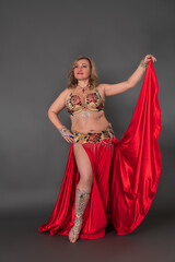 Good looking fashion model woman wearing bralette and crimson long skirt with slit, moves barefoot