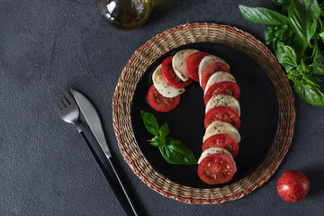 Italian Caprese salad in form of cane, with tomatoes, mozzarella cheese, basil and olive oil, Top view