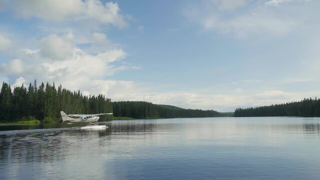 Wide establishing static of seaplane resting on open lake water with expansive forest landscape, Seignurie Du Triton Quebec Canada