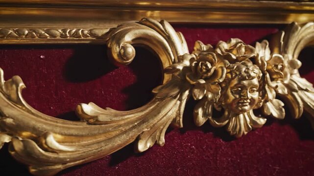 Decorative gold ornament close up. Luxurious rococo detail on antique frame. Elaborate baroque design on velvet surface.