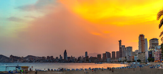 Fototapeta premium Golden hour sunset at Benidorm's bay with skyscrapers and buildings sunlight reflection on beach water