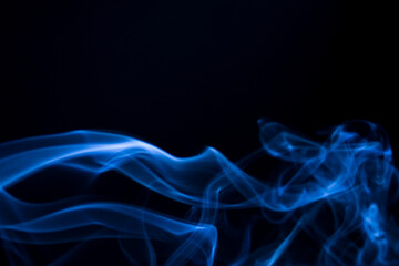 Obraz premium Abstract blue smoke billowing against a dark backdrop. The wisps of smoke create dynamic patterns and textures