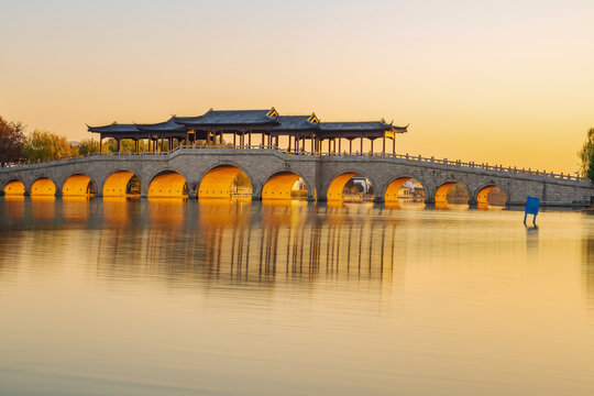 On the morning of December 8, 2025, golden sunlight shone through an ancient covered bridge over Jinji Lake in Suzhou, China