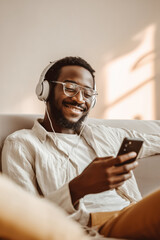 Man enjoying music while using smartphone at home