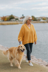 A woman strolls along a path with her fluffy dog