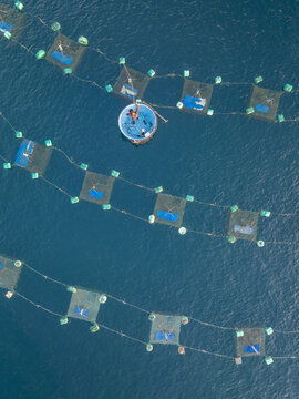 Aerial view of geometric fish farms float serenely on the deep blue sea, creating a mesmerizing pattern of nature and industry, Hon Yen, Phu Yen, Vietnam