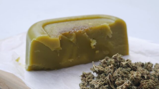 Close up shot of cannabis-infused butter (cannabutter) and a spatula on parchment paper, medicinal and edible marijuana concept.