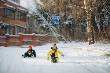 Mother son playing enjoying winter park snow sliding