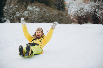 Woman sliding down snowy hill celebrating winter fun