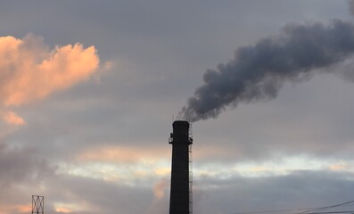 Smoke from the chimney of an industrial building at sunset