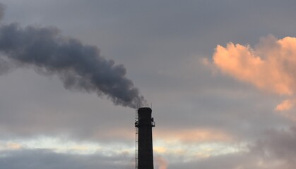 Smoke from the chimney of an industrial building at sunset