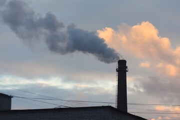 Smoke from the chimney of an industrial building at sunset