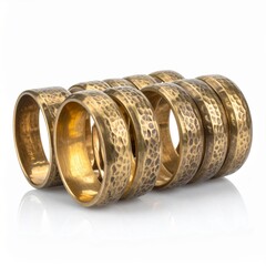 Stack of Golden Hammered Metal Rings on White Reflective Surface