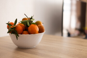 Full bowl of fresh tangerine on a wooden table.