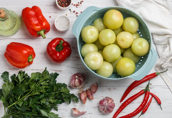 Green tomatoes, red bell pepper, hot chili pepper, garlic and parsley are the ingredients for making a spicy salad.