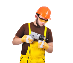 A bearded builder worker in an orange helmet and yellow overalls stanads with drill in hand.