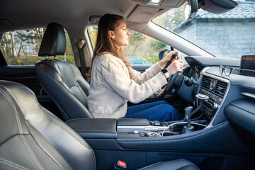 Naklejka premium Woman seated in driver seat of car, hands on wheel. Preparing for drive.