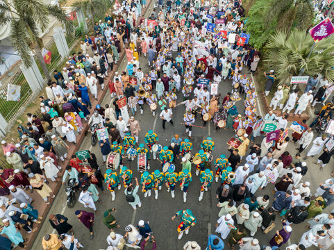 Aerial view of a vibrant street parade with musicians in green and yellow uniforms amidst a sea of people, Dhaka, Dhaka Division, Bangladesh.