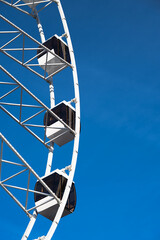 Vertical shot of a Ferris wheel cabin under the clear blue sky .  Copy space