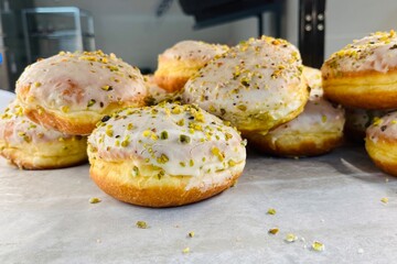 Pile of fresh glazed donuts topped with crushed pistachios, perfect for bakery photography or dessert promotions.