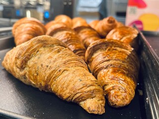 Freshly baked croissants with a golden flaky crust displayed on a baking tray in a professional bakery kitchen. Artisan pastry, crisp layers and warm homemade bakery atmosphere.