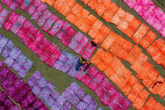 Aerial view of colorful dyed fabrics creating a vibrant mosaic on the lush green field, Narayanganj, Dhaka Division, Bangladesh.