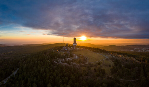 Aerial view of Grosser Feldberg's tower piercing the sky as the setting sun casts a golden glow over the landscape, Schmitten im Taunus, Hessen, Germany.