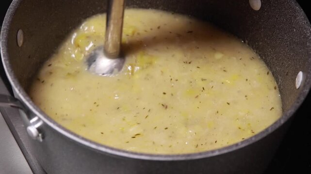 potato and leek soup being blended to a smooth, creamy texture in a pot
