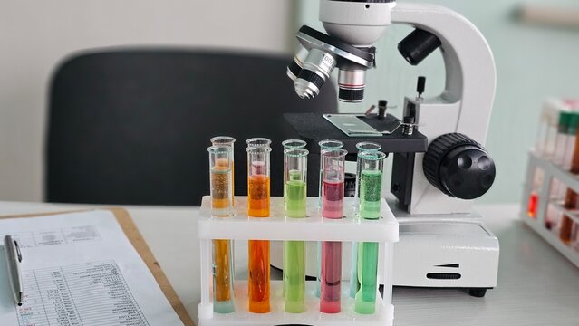 Laboratory setup with microscope and test tubes containing different colored liquids concept - Powered by Adobe