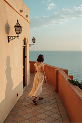 Woman walking on coastal terrace with ocean view in warm Mediterranean light