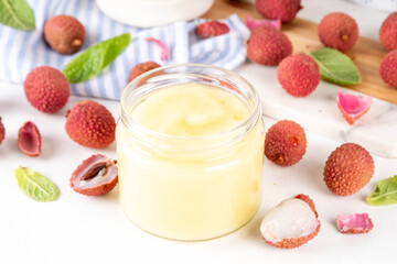 Homemade Lychee jam marmalade in jar, with fresh ripe lychees fruits on white table background, copy space
