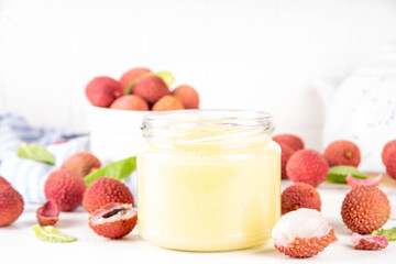 Homemade Lychee jam marmalade in jar, with fresh ripe lychees fruits on white table background, copy space