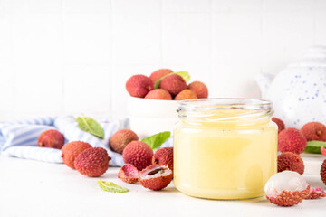 Homemade Lychee jam marmalade in jar, with fresh ripe lychees fruits on white table background, copy space