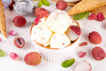 Tasty lychee sorbet ice cream. Lychee fruit gelato, in portioned bowl, on white pink background, with a lot of fresh lychees and waffle ice cream cones, copy space