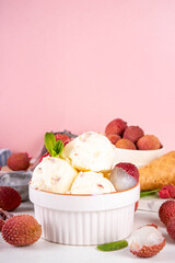 Tasty lychee sorbet ice cream. Lychee fruit gelato, in portioned bowl, on white pink background, with a lot of fresh lychees and waffle ice cream cones, copy space