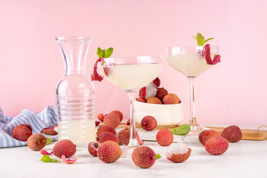 Lychee fruit tasty martini cocktail. Tasty alcohol drink with fresh lychees, mint leaves, liqueur and sweet sour juice, on white pink table background with ripe raw lychee fruits, copy space