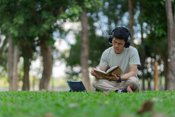 Obraz premium A peaceful young man is relaxing on the lawn, sipping coffee, smiling, listening to music, and conversing calmly. This promotes good health, concentration, peace, happiness, and harmony.